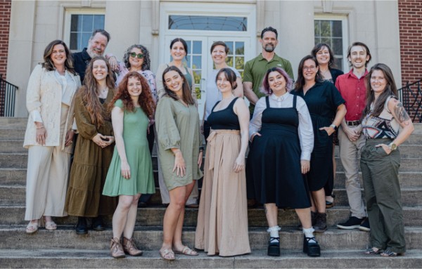 Several people in professor dress standing on the front steps of a building.